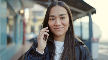 Genç, güzel İspanyol kadın, gülümsüyor. Kafe terasında akıllı telefondan konuşuyor.