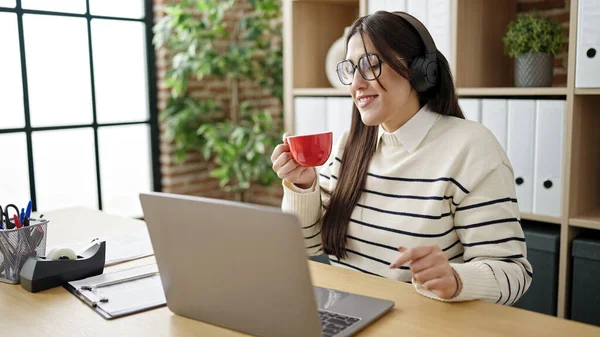 若い美しいヒスパニック系女性のビジネスワーカーは オフィスでコーヒーを飲む音楽を聞いて — ストック写真