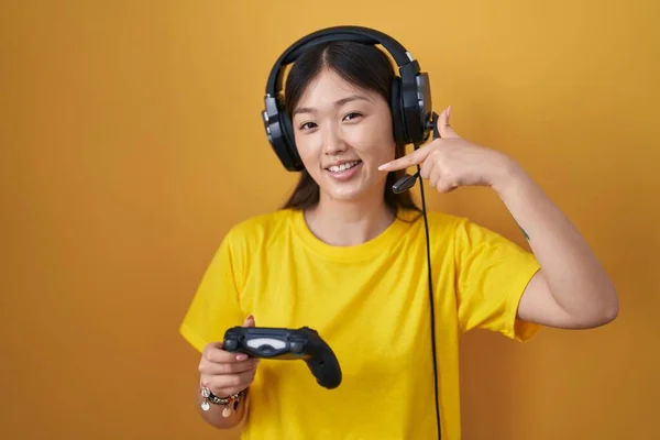 中国的年轻女子拿着游戏控制器 笑容满面 用手指 牙齿和嘴指指指点点 牙齿健康概念 — 图库照片