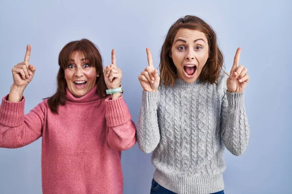 Mother Daughter Standing Blue Background Smiling Amazed Surprised Pointing Fingers — Stock Photo, Image