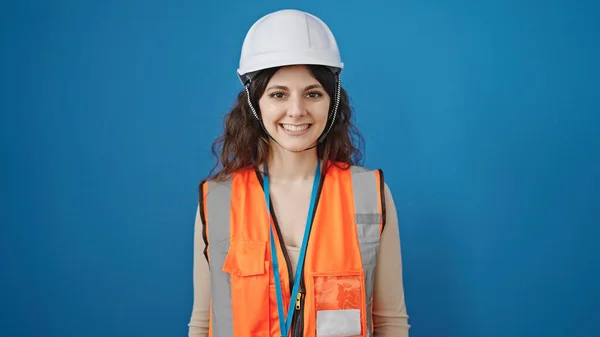 惊慌失措的女建筑工人微笑着 自信地站在孤立的蓝色背景之上 — 图库照片