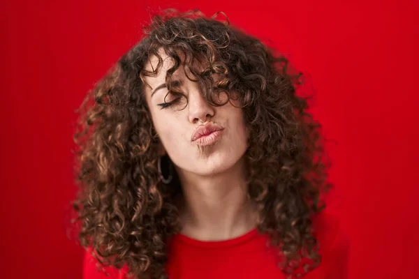 Spaanse Vrouw Met Krullend Haar Rode Achtergrond Kijkend Naar Camera — Stockfoto