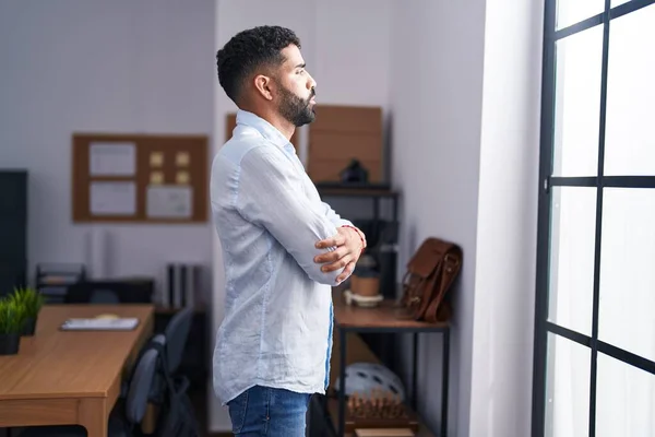 stock image Young arab man business worker looking throw the window with arms crossed gesture at office