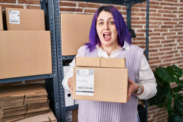 另外一个身材魁梧的女人在小企业工作时 她的头发是紫色的 她拿着盒子庆祝胜利 睁大了眼睛兴奋地尖叫着 — 图库照片