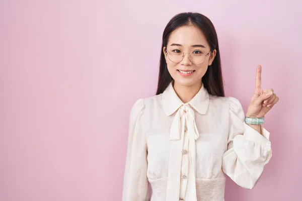 Mladá Číňanka Stojící Nad Růžovým Pozadím Ukazující Ukazující Prstem Číslo — Stock fotografie