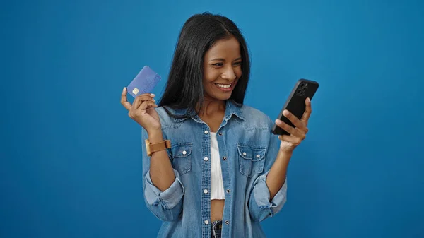 Afroamerikanerin Kauft Mit Smartphone Und Kreditkarte Vor Isoliertem Blauen Hintergrund — Stockfoto