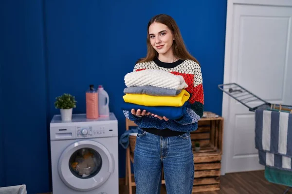stock image Young hispanic girl holding clean laundry winking looking at the camera with sexy expression, cheerful and happy face. 