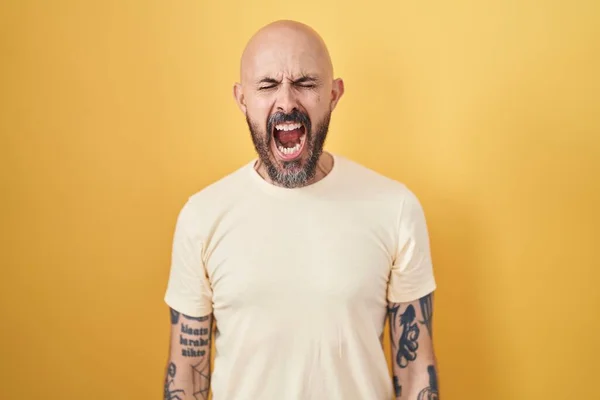 Sarı Arka Planda Dikilen Spanyol Dövmeli Adam Kızgın Öfkeli Çığlıklar — Stok fotoğraf