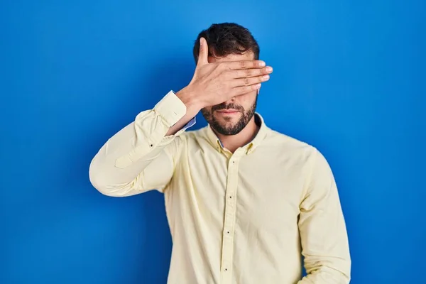 Handsome Hispanic Man Standing Blue Background Covering Eyes Hand Looking — Stock Photo, Image