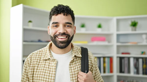 Young hispanic man student smiling confident wearing backpack at library university