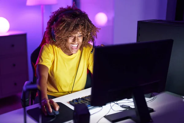 stock image African american woman streamer playing video game using computer at gaming room