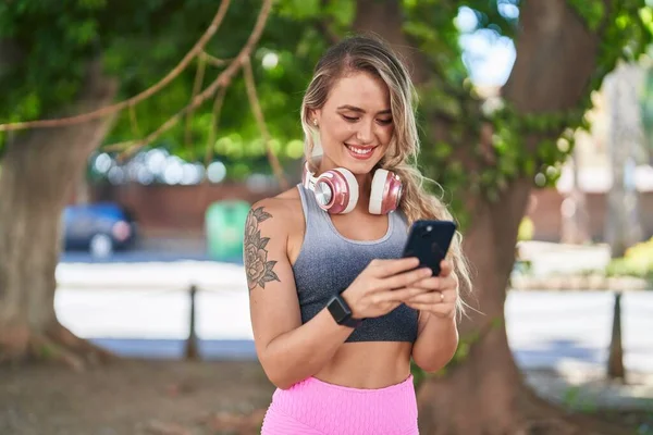 公园里穿着运动服的金发女青年用智能手机 — 图库照片