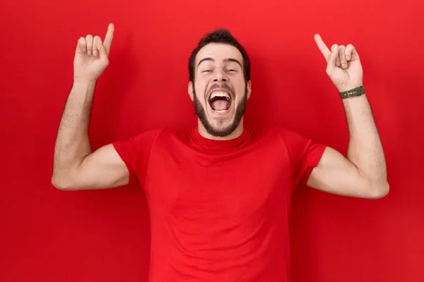 Νεαρός Ισπανός Που Φοράει Κόκκινο Μπλουζάκι Χαμογελώντας Έκπληκτος Και Δείχνοντας — Φωτογραφία Αρχείου