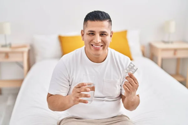 Jovem Latino Sorrindo Confiante Segurando Pílulas Vidro Água Quarto — Fotografia de Stock