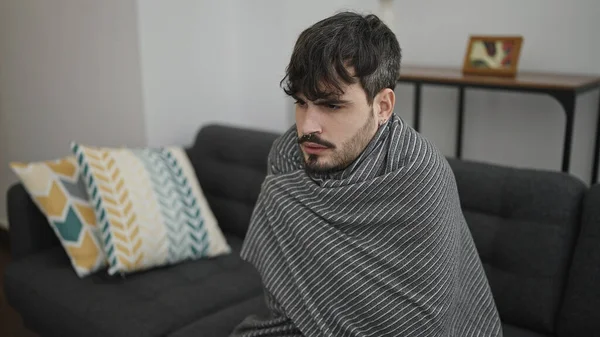 年轻的惊慌失措的男人感到家里被毛毯盖住了很冷 — 图库照片