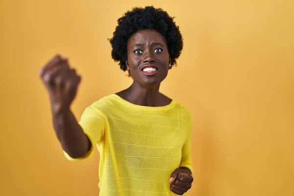 怒り狂った黄色のスタジオの上に立っているアフリカの若い女性は怒りで叫んでいる間に拳をフラストレーションと激怒させました 怒りと攻撃的な考え方 — ストック写真