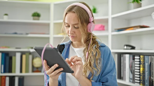 Młoda Blondynka Student Pomocą Touchpad Słuchawki Uniwersytecie Biblioteki — Zdjęcie stockowe