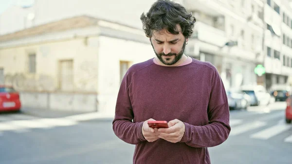 stock image Young hispanic man using smartphone with serious expression at street