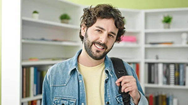 Young hispanic man student smiling confident wearing backpack at library university