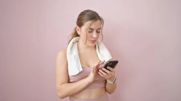 Młoda Blondynka Nosi Odzież Sportową Pomocą Smartfona Odizolowanym Różowym Tle — Zdjęcie stockowe