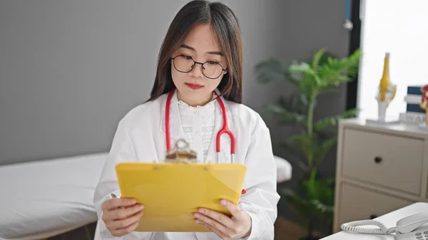 若いです中国人女性医師読書ドキュメント上のクリップボードにクリニック — ストック写真