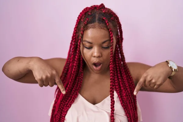 Африканская Американка Плетеными Волосами Стоит Розовом Фоне Указывая Вниз Пальцами — стоковое фото