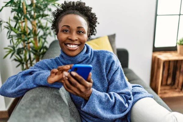 Αφροαμερικανή Γυναίκα Που Χρησιμοποιεί Smartphone Κάθεται Στον Καναπέ Στο Σπίτι — Φωτογραφία Αρχείου