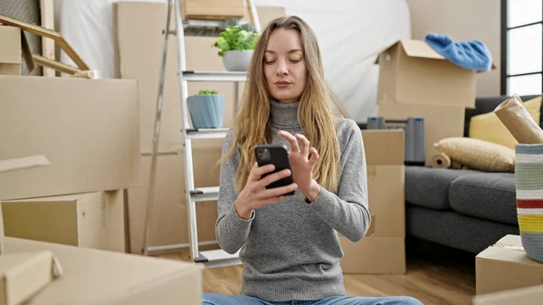 Beyaz Bir Kadın Yeni Evinde Akıllı Telefon Kullanarak Yerde Oturuyor — Stok fotoğraf