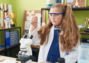 Sevimli sarışın kız öğrenci laboratuvar sınıfında örnek arıyor.