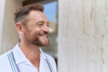 Middle age man smiling confident looking to the side at street