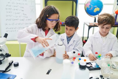 Bir grup öğrenci laboratuvar sınıfında deney yaparak şişenin üzerine sıvı döküyorlar.