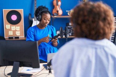 African american women musicians using smartphone at music studio