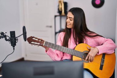 Genç İspanyol kadın müzisyen müzik stüdyosunda gitar çalıyor.