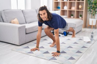 Genç İspanyol adam gülümseyerek evde kendine güvenen yoga eğitimi alıyor.