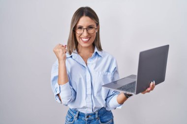 Bilgisayarı kullanan genç bir kadın çok mutlu ve heyecanlı bir şekilde kollarını kaldırıp, gülümseyerek ve başarı için çığlık atarak kazanan bir jest yapıyor. kutlama konsepti. 