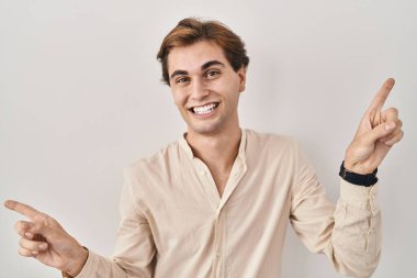 İzole edilmiş arka planda duran genç adam farklı yönleri gösteren kendine güveniyle gülümsüyor. reklam için kopyalama alanı 