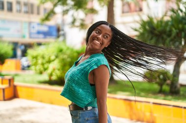 Afro-Amerikalı kadın parkta kendine güvenen gülümsüyor.