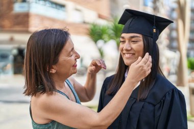 Two women mother and graduated daughter standing together at street