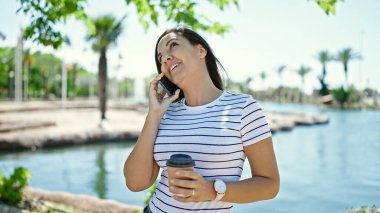 Orta Doğulu kadın deniz kenarında telefonla konuşuyor.