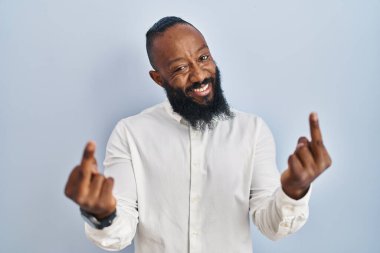 African american man standing over blue background showing middle finger doing fuck you bad expression, provocation and rude attitude. screaming excited 