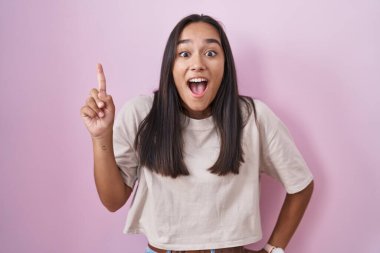 Pembe arka planda duran genç İspanyol kadın başarılı bir fikri işaret ediyor. Heyecanlı ve mutlu. Bir numara.. 