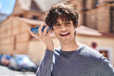 Genç İspanyol adam gülümsüyor. Caddedeki akıllı telefondan kendine güvenen bir sesli mesaj dinliyor.
