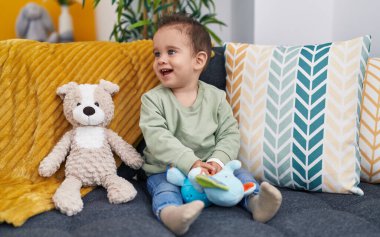 Evdeki kanepede otururken kendine gülen sevimli İspanyol çocuk.