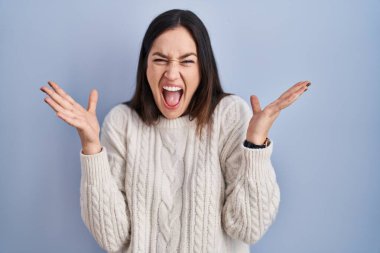 Mavi arka planda duran genç esmer kadın çılgın ve başarıyı kollarını kaldırıp heyecanla haykırarak kutluyor. Kazanan konsept 