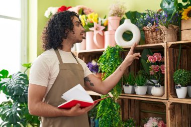 Çiçekçide kitap okuyan genç Latin bir çiçekçi.