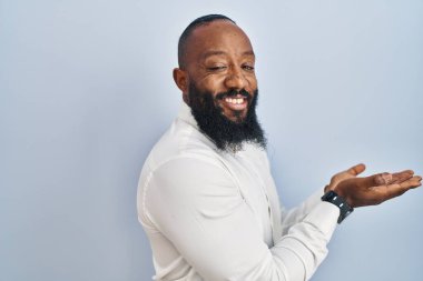 Mavi arka planda dikilen Afro-Amerikalı adam avuçlarını açıp fotokopi alanını gösteriyor. 