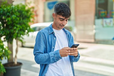 Sokakta akıllı telefon kullanan, kendine güvenen genç bir İspanyol.