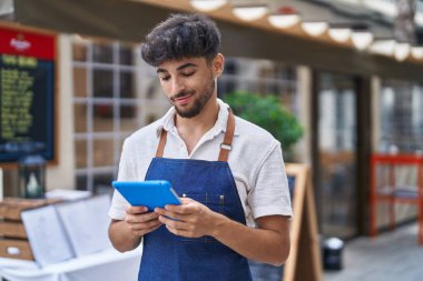 Young arab man waiter using touchpad working at restaurant