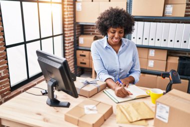 African american woman ecommerce business worker writing on notebook at office