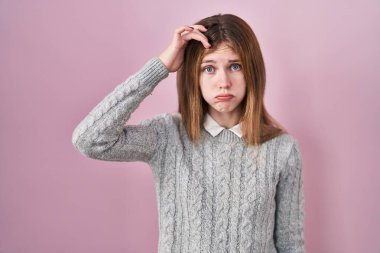 Güzel bir kadın pembe arka planda duruyor. Alnındaki sorun yüzünden endişeli ve stresli. Kriz için endişeli. 